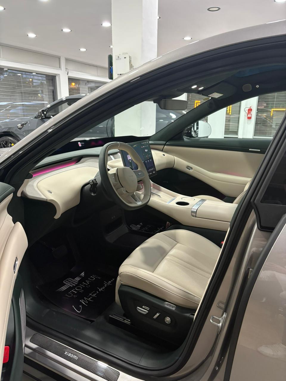 Xiaomi YU7 Max — intérieur avant côté conducteur, sellier crème accents vert sapin, tapis Autohaus Tanger